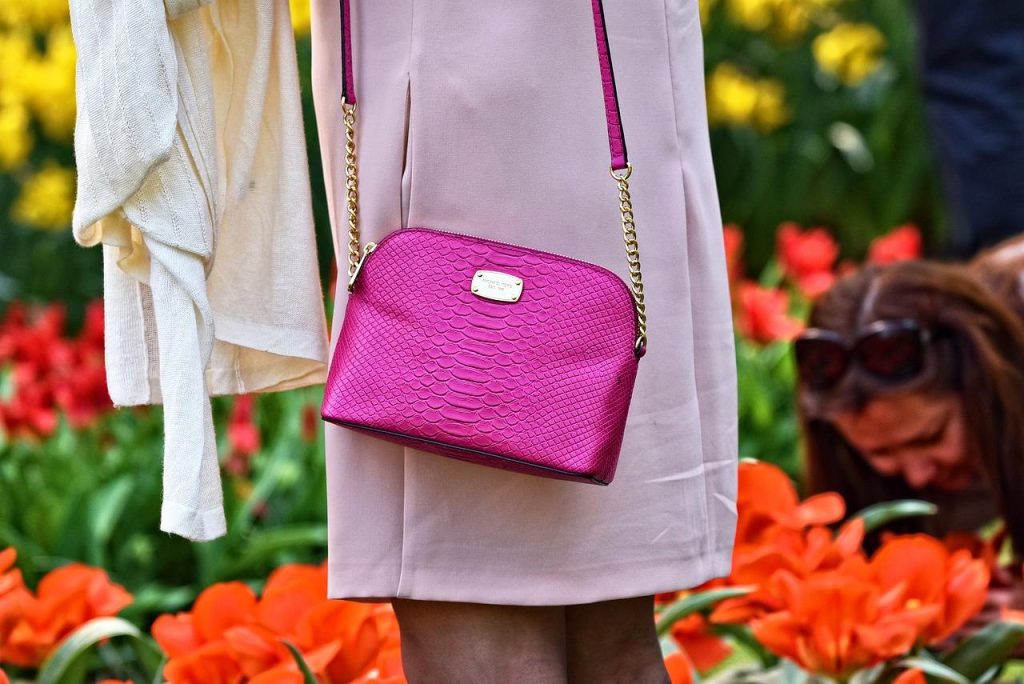 Vrouw met roze tas gecombineerd met neutrale kleding in een casual outfit